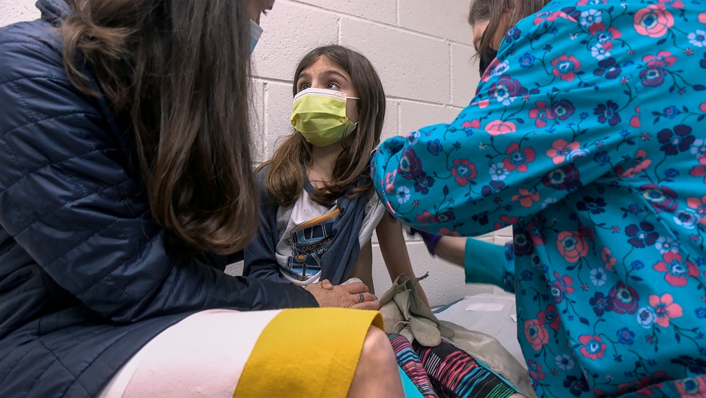 In this March 24, 2021 image, Alejandra Gerardo, 9, looks up to her mom, Dr. Susanna Naggie, as she gets the first of two Pfizer COVID-19 vaccinations during a clinical trial for children at Duke Health in Durham, N.C. (Shawn Rocco/Duke Health via AP)