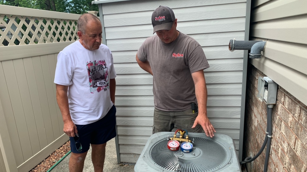 Gary Remillong looks on as Syles Mechanical Services HVAC service technician, Allan St. Denis repairs his air conditioner in Tecumseh, Ont. on Wednesday, June 22, 2022. (Chris Campbell/CTV News Windsor)
