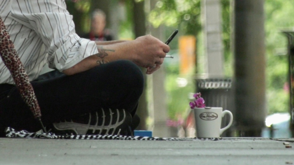 A panhandler sits on a sidewalk on Ouellette Avenue in Windsor, Ont., July 13, 2022. (Rich Garton/CTV News Windsor)