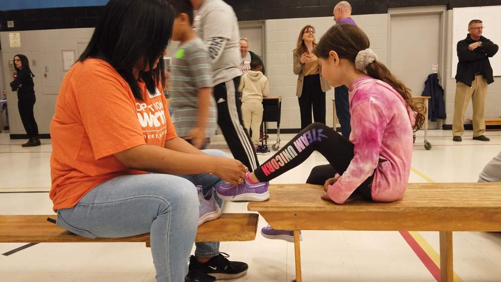 Volunteer from Operation Warm helping a student lace up her new shoes at St. James Catholic Elementary School in Windsor, Ont. on Thursday, April 27, 2023. (Source: WECDSB)